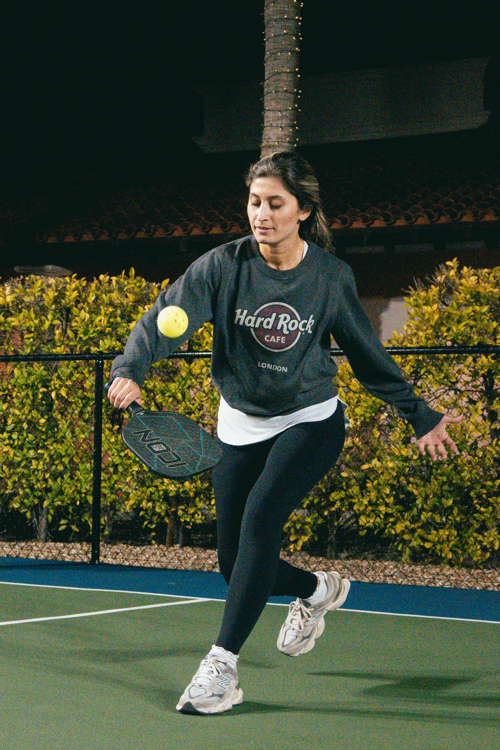 Energetic woman playing pickleball on an outdoor court under night lighting in Scottsdale, Arizona.
